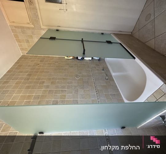 אמבטיה עם דלתות זכוכית חלבית ומוצרים על הקצה